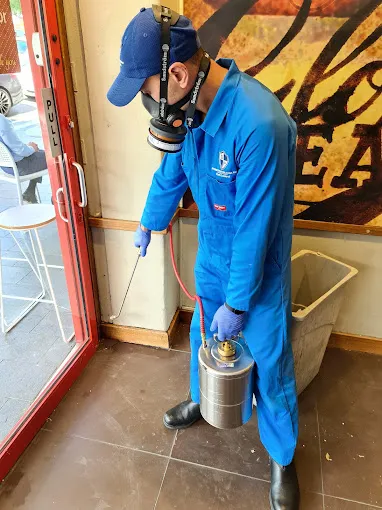 Technician spraying a cafe perimeter near the entrance